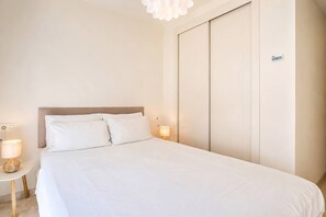 A hotel room with a large bed, bedside lamps, a wall-mounted control panel, and a ceiling light fixture. - VR1B - Golfside Escape Near Estepona (Estepona)