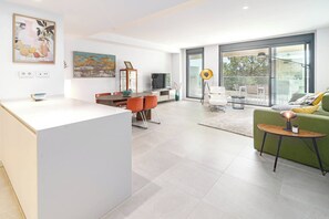 A modern living room with a dining area, a sofa, a TV, and artwork on the walls. - VV6-2B - Modern 2BR with large seaview balcony (Estepona)