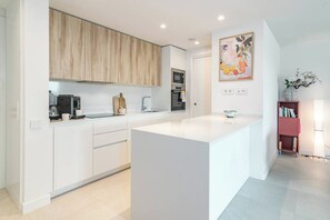 Een moderne keuken met witte kasten, een centraal eiland en een magnetron boven het aanrecht.