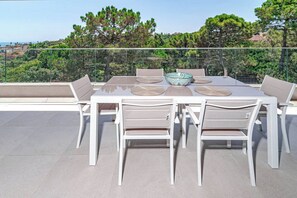 A dining area with a table and chairs, a decorative bowl, and a view of trees and buildings. - VV6-2B - Modern 2BR with large seaview balcony (Estepona)