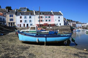 A boat moored on a pebbly shore with buildings in the background. - Cottage 'Kêr Didrouz' with Private Terrace, Private Garden and Wi-Fi (Le Palais)