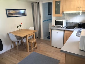 A compact kitchen with a dining area, a refrigerator, a microwave, a toaster, and a sink. - Cottage 'Kêr Didrouz' with Private Terrace, Private Garden and Wi-Fi (Le Palais)