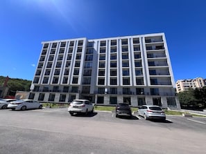 A multi-story building with a parking lot in front. - Felic Home Stylish apartment overlooking the forest (Tsaghkadzor)