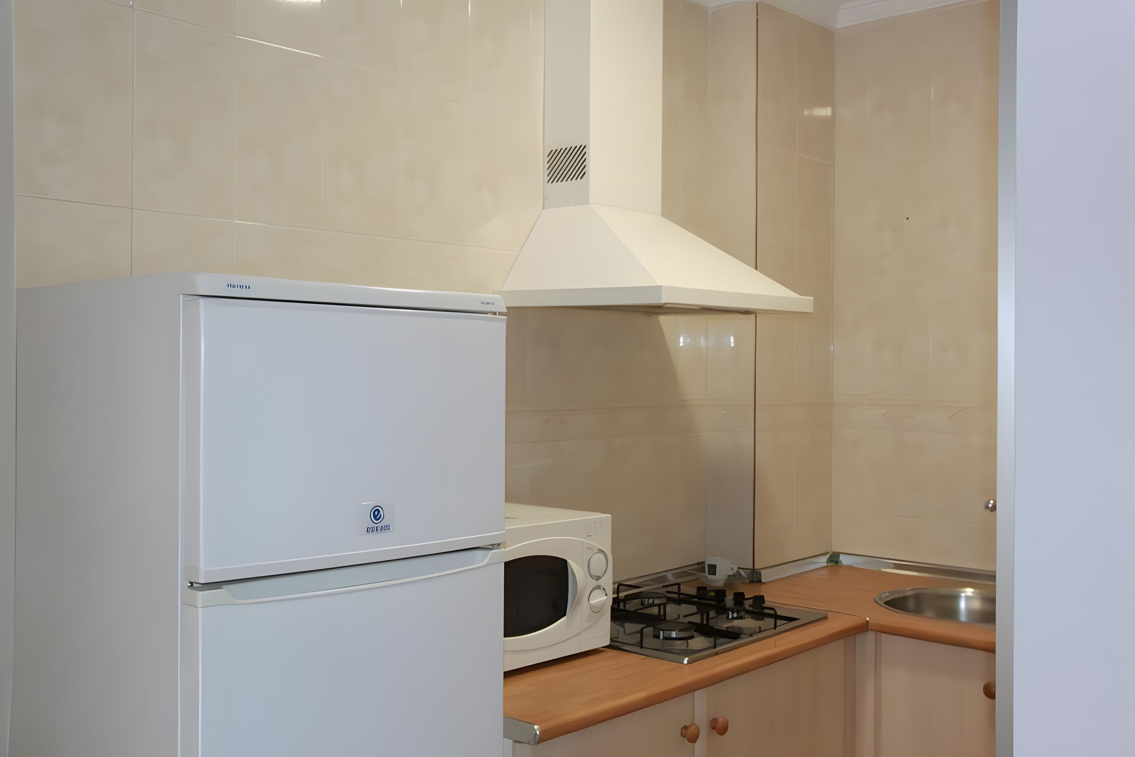 A compact kitchen with a refrigerator, microwave, stove, and cabinets.