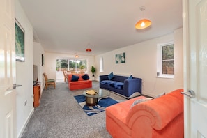 A spacious living area with a sofa, a coffee table, and a dining area with chairs. - Newport Residence (Newport)