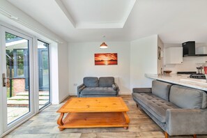 A modern living room with a sofa, a coffee table, and a dining area with a kitchen counter. - Newport Residence (Newport)
