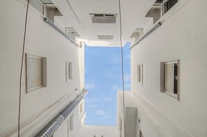 A narrow alleyway between buildings with white facades and multiple windows, leading to a clear blue sky. - Apartamento 'el yunque- solo familias' (Conil de la Frontera)