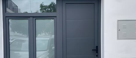A garage entrance with a grey door, a car parked inside, and a metal utility box on the wall.