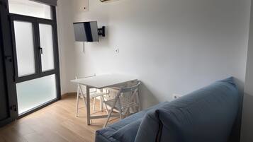 Et værelse med et hvidt bord, stole, en blå sofa, en skydedør af glas og en fastgjort aircondition.