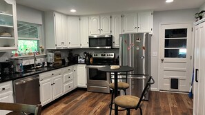 A modern kitchen with white cabinetry, stainless steel appliances, and a wooden floor. - Beautiful 2-bedroom house with huge fenced yard in delightful Chattanooga (Chattanooga)