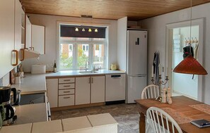 Una cocina con ventana, un refrigerador y un comedor con mesa y sillas.