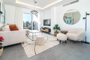 A modern living room with a sofa, armchair, coffee table, and a large window. - RDM9- Modern family apartment in Riviera del Mar (Mijas)