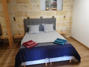 Una cama con ropa de cama estampada, dos almohadas y dos toallas dobladas.