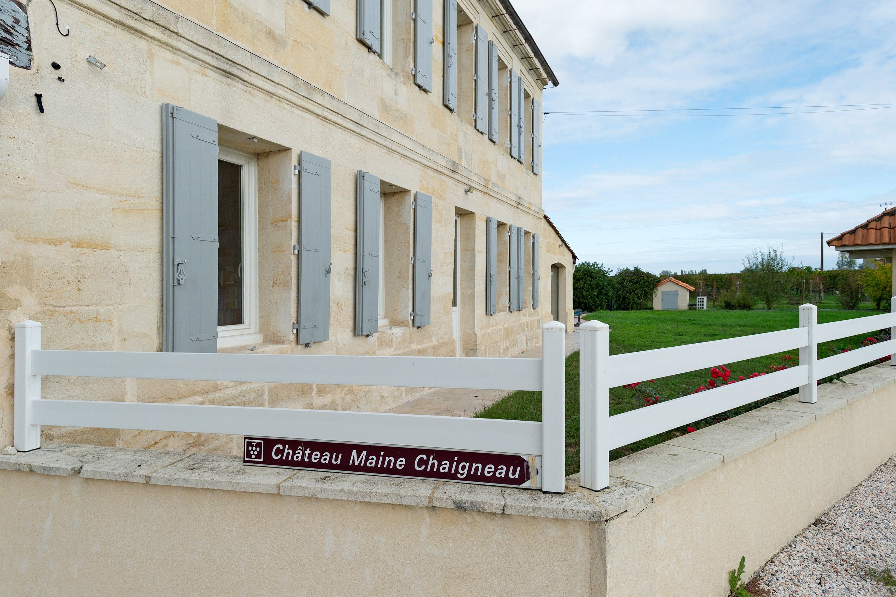 A stone building with a white fence and a sign reading 'Chateau Maine Chaignéau'.