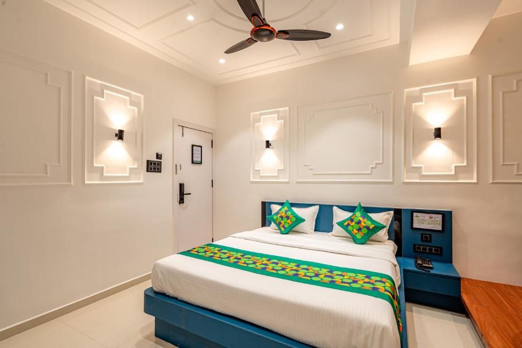 Quarto de hotel com cama, mesa de cabeceira, luminárias fixadas na parede e ventilador de teto.