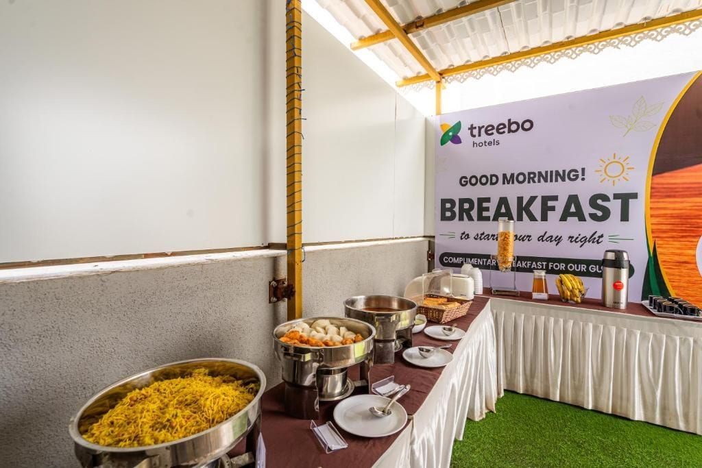 Een ontbijtbuffet met diverse gerechten en een banner voor Treebo Hotels.