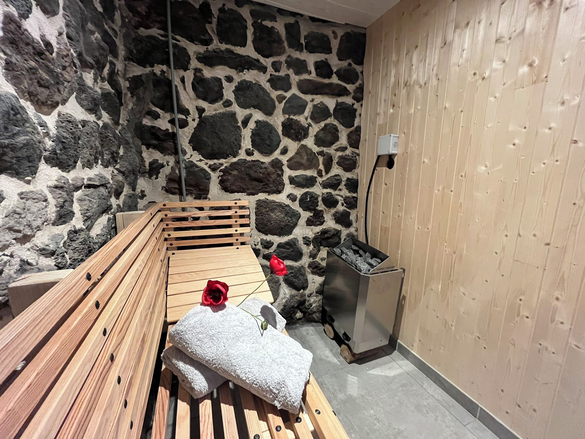 Un sauna aux murs de pierre, avec un banc en bois et un petit chauffage.