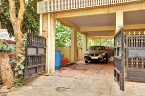 A covered parking area with a car parked inside, a gated entrance, and a signboard. - Hotel O Metro Inn Manyata (Bengaluru)