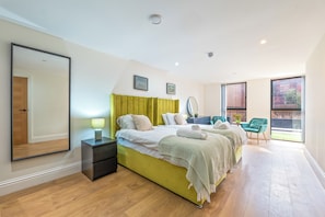 A modern bedroom with a large bed, bedside tables, a mirror, and a view of the outdoors. - Luxury 4 Bed | Jewellery Quarter | Private Parking (Birmingham)