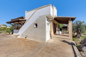 Ein modernes Haus mit einer Stein-Fassade, einem kleinen Fenster und einer überdachten Terrasse.