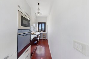 Eine moderne Küche mit Edelstahlgeräten, einer Holz Arbeitsplatte und Blick ins Freie.