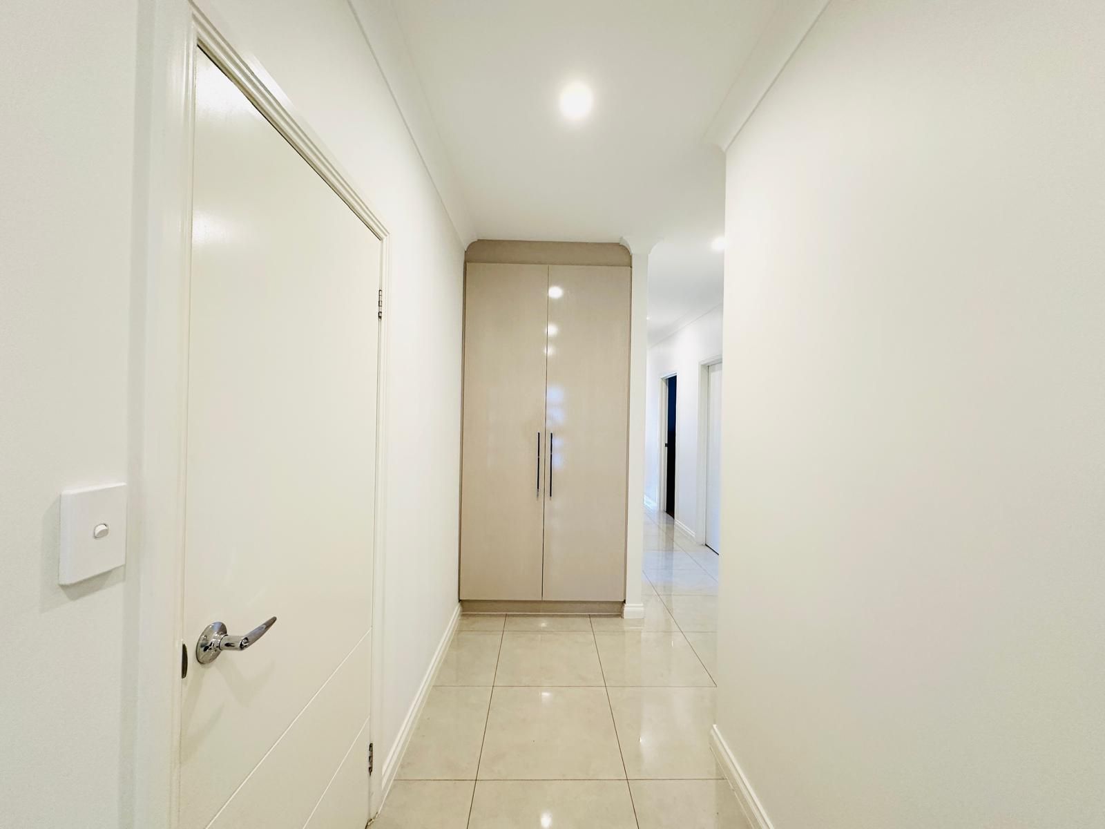 A corridor with a door on the left, a wardrobe in the center, and a hallway extending to the right.
