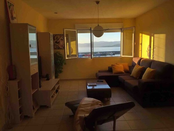 A living room with a sofa, a coffee table, a TV, and a large window with a view of the sea. - Holiday Home 'Casa vacacional' with Sea View and Terrace (Goyanes)
