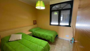A room with two beds, a window with blinds, a wall-mounted light fixture, and a small picture frame. - Holiday Home 'Casa vacacional' with Sea View and Terrace (Goyanes)