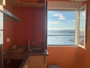 A kitchen with a large window, red tiles, and a view of the sea. - Holiday Home 'Casa vacacional' with Sea View and Terrace (Goyanes)