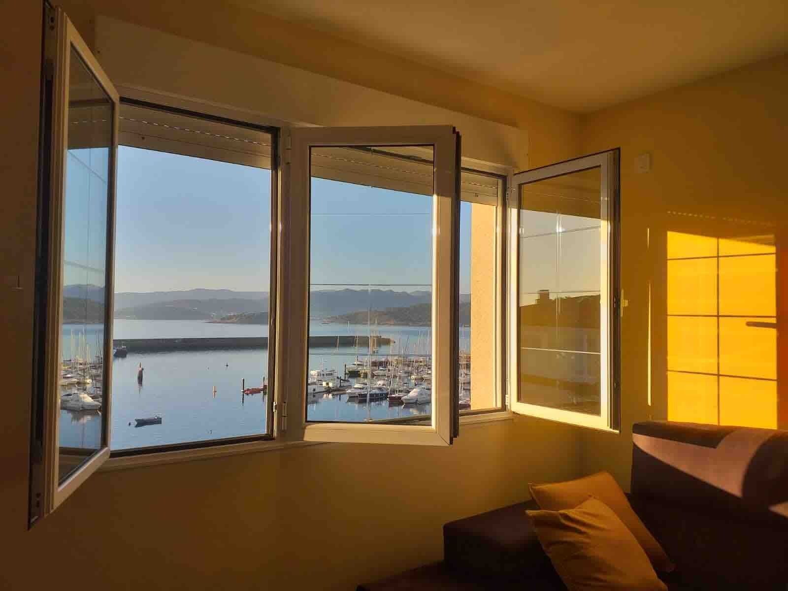 Una habitación con un amplio ventanal con vistas a un puerto deportivo con barcos.