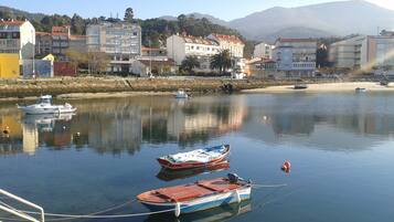 A calm waterfront with boats docked, buildings in the background, and a clear sky.