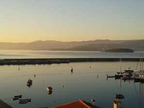 A marina with boats docked, calm water, and a distant mountain range.