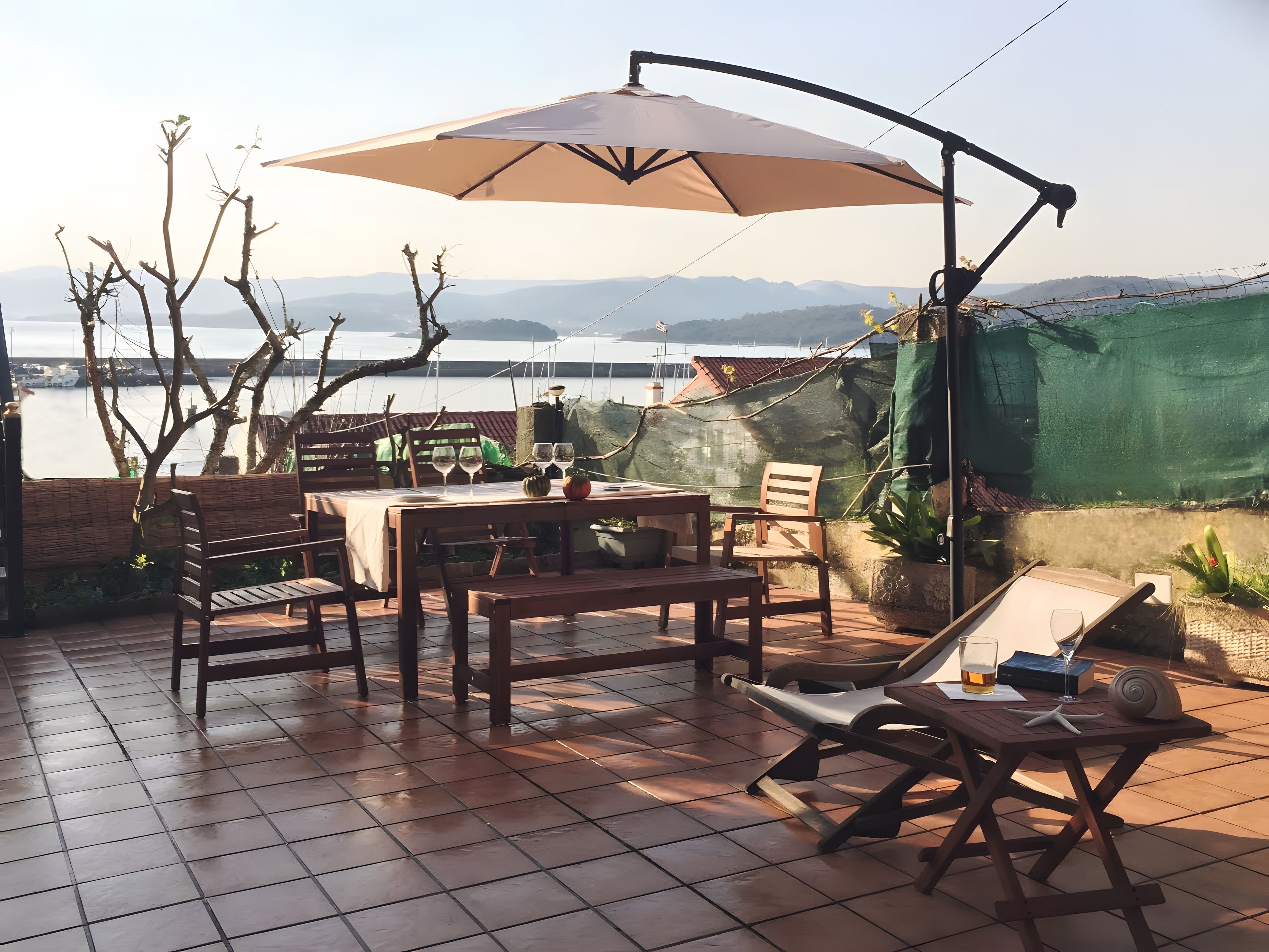 Un patio al aire libre con una mesa lista para comer, un banco y una silla de descanso.