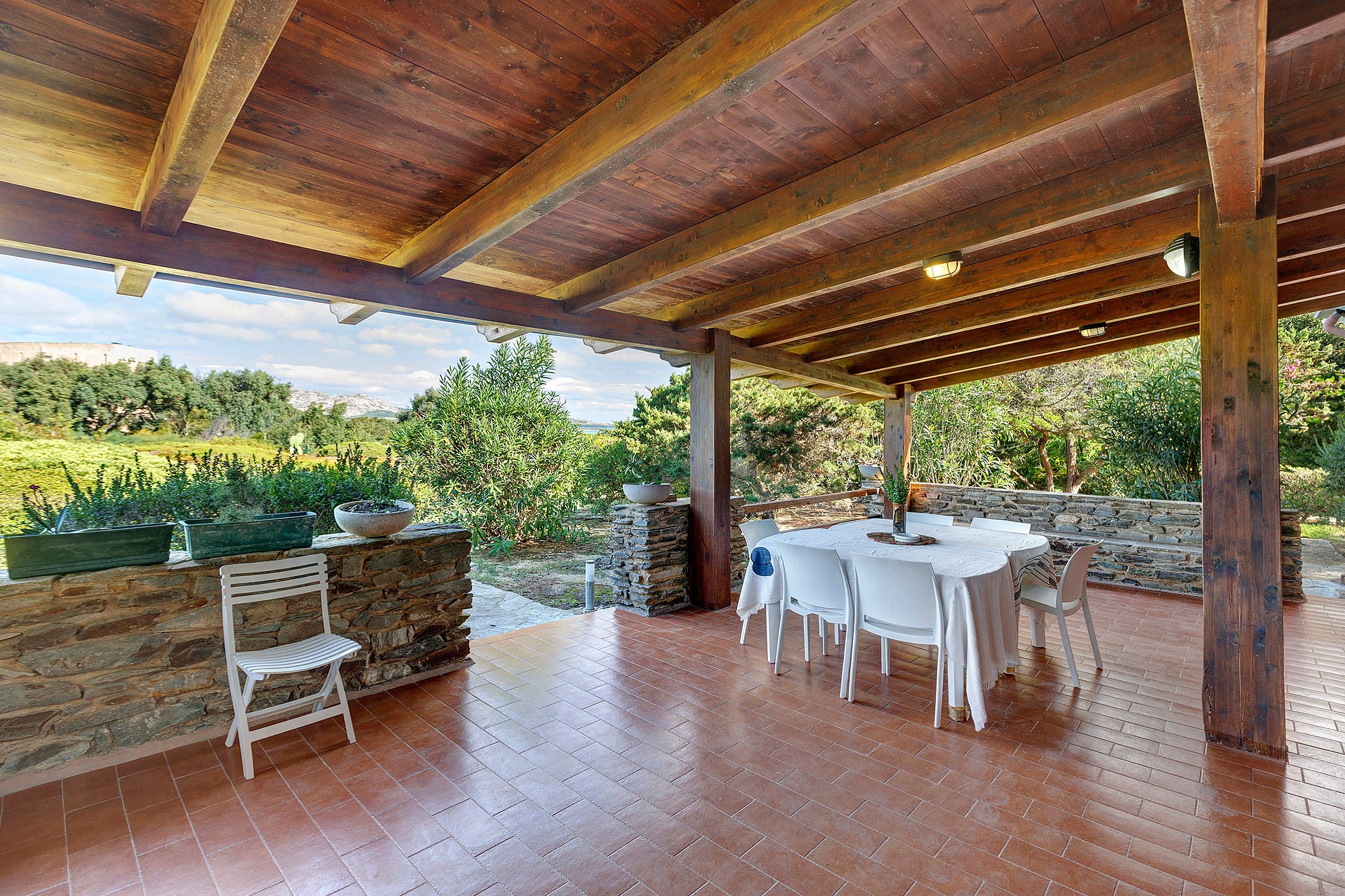 An outdoor patio with a stone wall, a white table, and chairs.