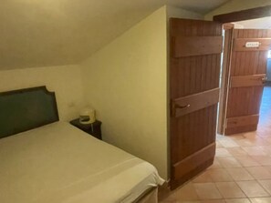 A bedroom with a bed, a nightstand, and a wooden door. - Villa 'Cosmi' with Relaxation and Panoramic View near La Pelosa (Stintino)