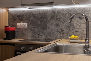 A modern kitchen with a built-in oven, a sink, and a countertop with a coffee maker and lemons. - Harokopou 3·HM1·ground (Kallithea)