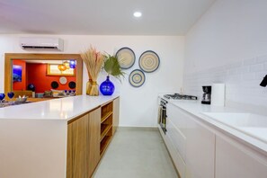 A modern kitchen with white cabinetry, a built-in oven, and a coffee maker. - Cozy Modern Condo Steps to Everything (Puerto Vallarta)