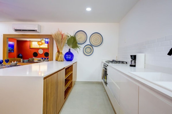 Una cocina moderna con armarios blancos, horno empotrado y cafetera.