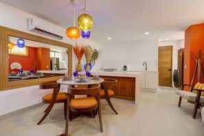 A modern kitchen with a central island, a dining area with a round table and chairs, and a large mirror on the wall. - Cozy Modern Condo Steps to Everything (Puerto Vallarta)