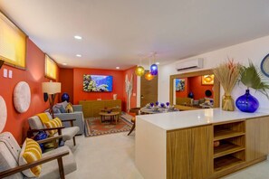 A modern living room with a sofa, a coffee table, and a TV mounted on the wall. - Cozy Modern Condo Steps to Everything (Puerto Vallarta)