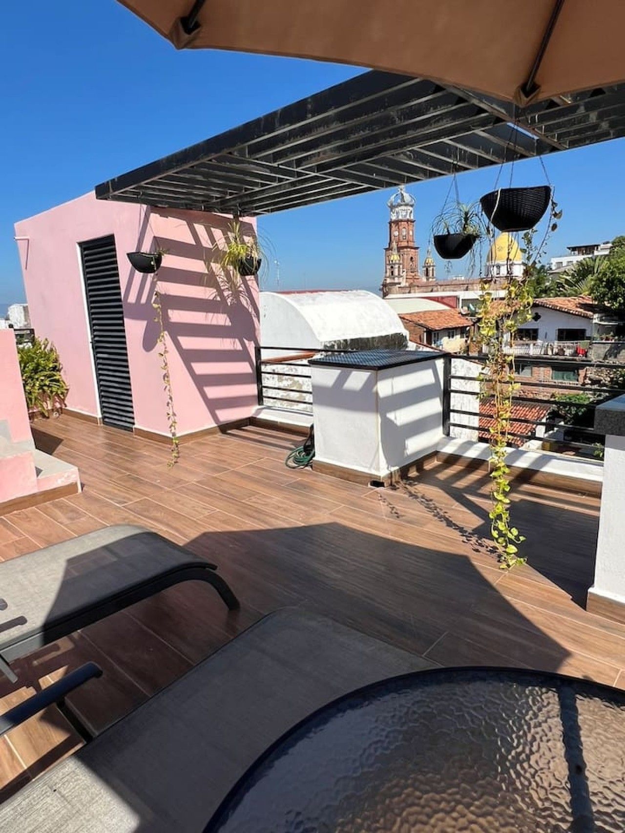 A rooftop terrace with a pergola, seating area, and hanging planters.