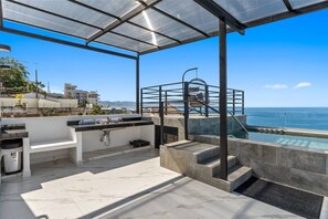 A rooftop terrace with a pool, outdoor seating, and a view of the ocean. - Bright & Breezy 1BR with Balcony (Puerto Vallarta)