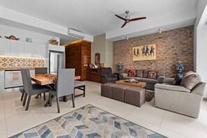 A modern living room with a dining area, a brick accent wall, and a ceiling fan. - Stylish Zona Romántica Stay (Puerto Vallarta)