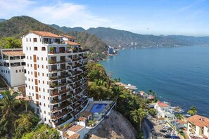 Ein mehrstöckiges Hotel mit Balkonen, einem Schwimmbad und Blick auf die Küste.