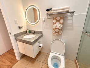 A bathroom with a round mirror, a sink, a toilet, and a towel rack with towels.