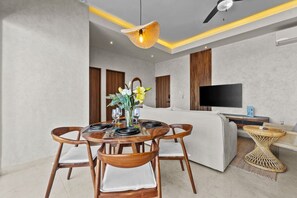 A modern living room with a dining area, a flat-screen TV, and a ceiling fan. - Modern 2BR Oasis in Centro | Easy walk to Malecon (Puerto Vallarta)