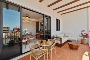 A modern interior with a dining area, a sofa, and a balcony with a view. - Modern 2BR Oasis in Centro | Easy walk to Malecon (Puerto Vallarta)