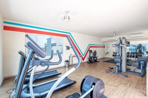 Et fitnesscenter med løbebånd, styrkemaskiner og en spejlvæg.