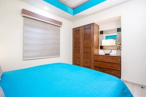 A bedroom with a bed, a wardrobe, a mirror, and a window with blinds. - Perfect One Bedroom one block from the Beach! (Puerto Vallarta)