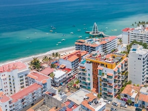 A coastal cityscape with a beachfront hotel, multiple buildings, and a clear view of the ocean. - Perfect One Bedroom one block from the Beach! (Puerto Vallarta)
